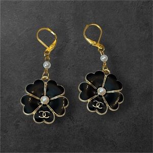 Black and gold earrings with a pearl in the center.